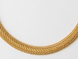 a close up of a gold necklace on a white surface