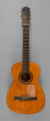 une vieille guitare posée sur une surface grise