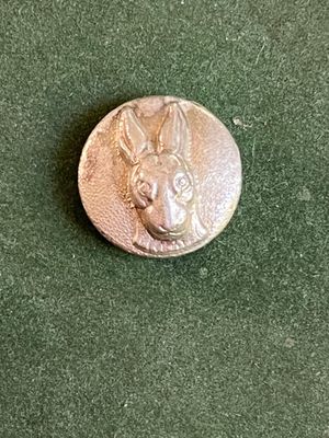 un gros plan d'un bouton en métal orné d'une tête de chien