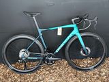 un vélo bleu garé contre un mur, devant un mur noir