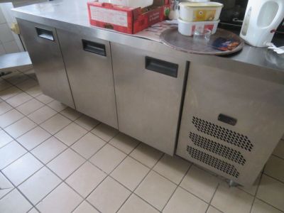un plan de travail en acier inoxydable dans une cuisine professionnelle équipée d'un micro-ondes