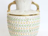 a white vase with a gold handle on a white background
