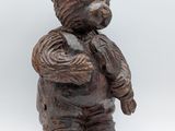 wooden statue of a teddy bear holding a bird in his hands