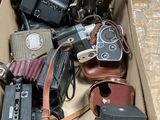 a cardboard box filled with old cameras and other items