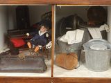 une poupée posée à l'intérieur d'une vitrine remplie d'objets