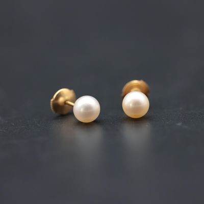 a pair of pearl earrings on a black surface