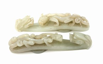 two pieces of carved jade hair clips on a white surface