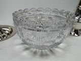 a glass bowl sitting on a table next to a silver plate