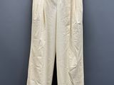 un pantalon blanc suspendu à un cintre devant un mur gris