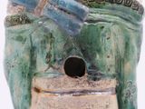 a blue and green vase with a bird on top of it
