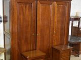 une armoire en bois, avec deux chaises et une table devant