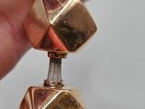 a person holding a pair of gold earrings on a string