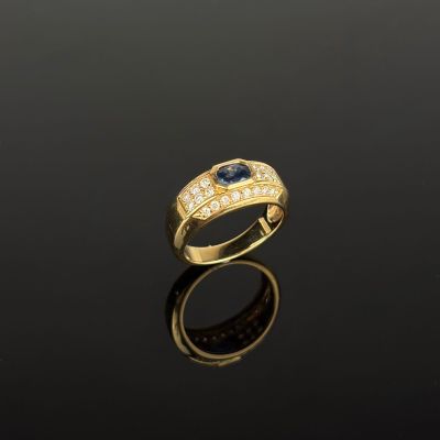 une bague en or sertie d'un saphir et de diamants sur un fond noir