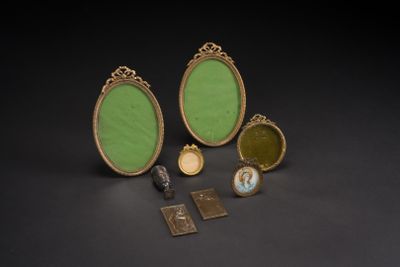 three gold and green oval frames with a key and other items
