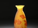 un vase jaune orné de fleurs orange posé sur une table