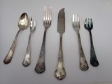several forks and spoons are lined up on a white surface