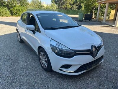 une voiture blanche garée sur un parking, avec des arbres en arrière-plan