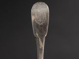 an old silver spoon sitting on top of a white plate