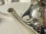 a silver tea pot sitting on a silver tray on a table