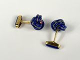 two pairs of blue and gold cufflinks on a white surface