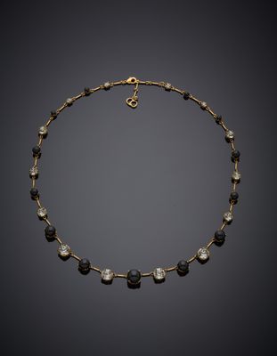 un collier noir et doré orné de perles de verre noires et blanches