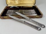 cinq pièces d'argenterie dans un coffret posé sur une table