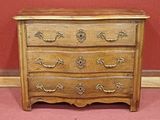 a small wooden chest of drawers on a carpeted floor