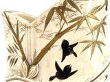 a white vase with black birds and bamboos on it