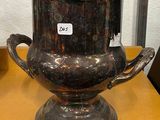 un vase en argent posé sur une table, avec une étiquette de prix dessus