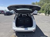 the back of a white car with its trunk open in a parking lot