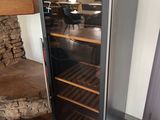 a wine cooler in the corner of a room next to a fireplace