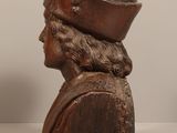 carved wooden bust of a man with a hat on top of his head