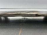 the rear end of a white car with a rusted exhaust pipe