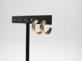 a pair of gold hoop earrings on a black stand
