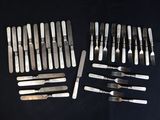 de nombreuses fourchettes et couteaux disposés sur une table