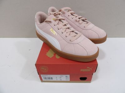 des baskets Puma roses à semelles en caoutchouc, posées sur une boîte rouge
