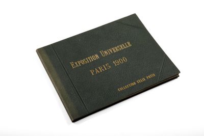an old black book with gold lettering on it sitting on a white surface