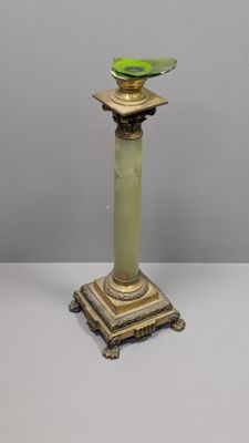 un vase vert posé sur un socle à la base dorée