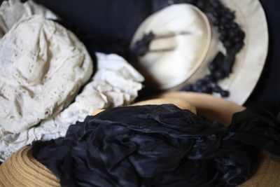un bol en bois recouvert d'un tissu noir, sur lequel est posé un chapeau