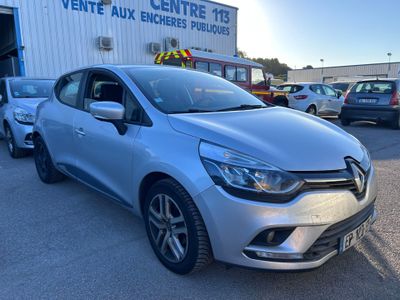Une voiture argentée est garée devant un immeuble.