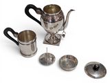 a silver tea pot and two cups on a white surface