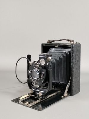 une vieille photo représentant un vieil appareil photo posé sur une surface blanche
