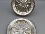 a pair of silver plated ashtrays on a table