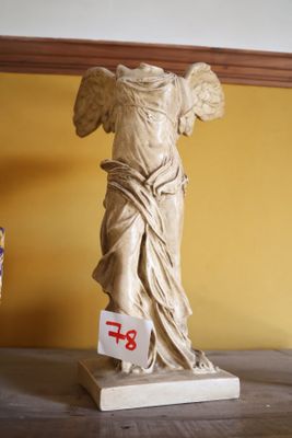 une statue d'ange posée sur un socle dans une pièce