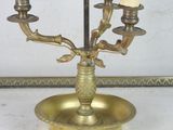 a brass table lamp that has three candles on it