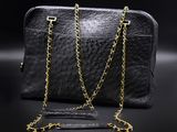 a black purse with gold chains on a black background
