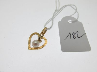 un pendentif en forme de cœur en or auquel est suspendue une perle
