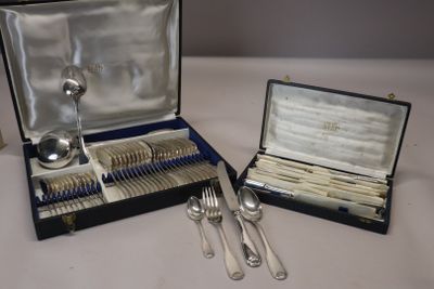 des couverts dans un coffret posé sur une table contenant d'autres couverts