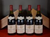 four bottles of wine are lined up on a red table