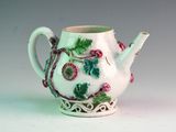 a white tea pot with green and pink decorations on it